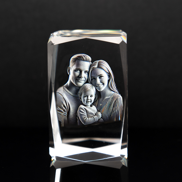 A beveled rectangular crystal with a 3D engraved image of a family of three inside it, displayed on a dark background.